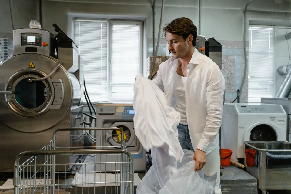 Une personne retire et nettoie le filtre d'un lave-linge blanc