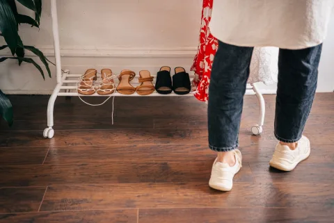 Une entrée de maison bien organisée avec des patères en bois, un banc de rangement et un miroir rond.