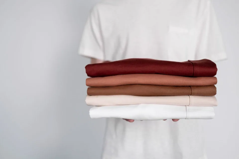 Une penderie parfaitement ordonnée avec des vêtements suspendus par couleur et des boîtes de rangement en tissu