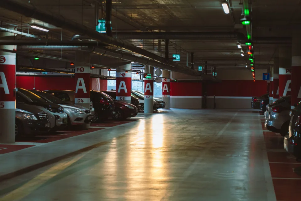Des dizaines de voitures garées sur un parking extérieur sécurisé près d'un aéroport.