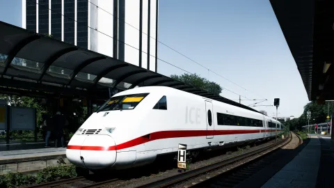 Un train à grande vitesse stationné à quai dans une gare européenne moderne avec des voyageurs.