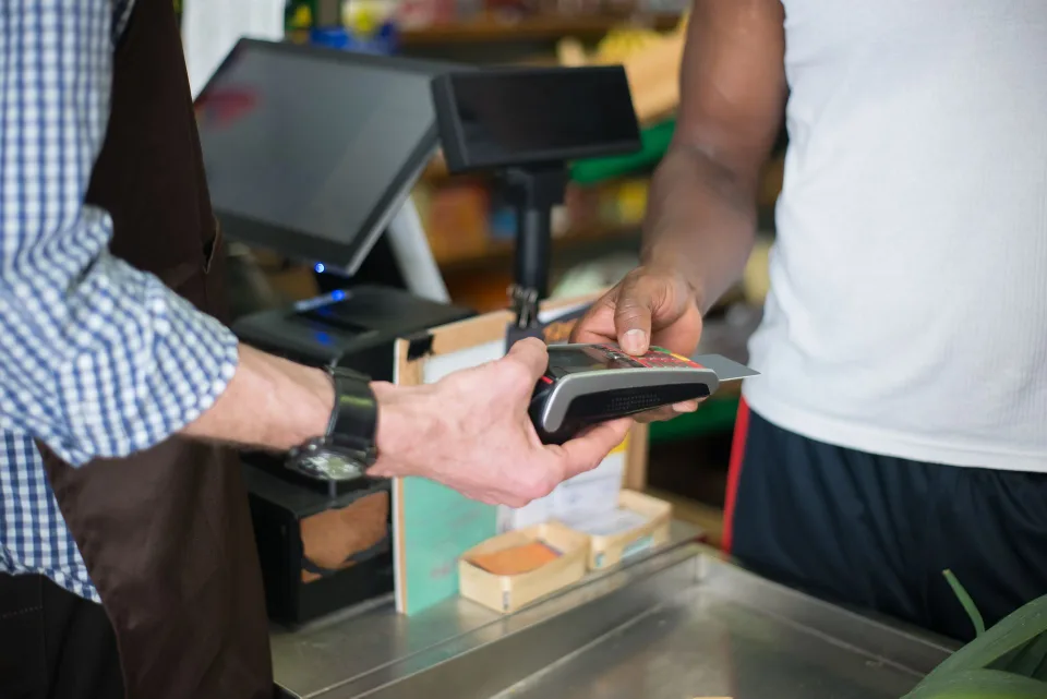 Une personne règle ses achats avec une carte bancaire sans contact auprès d'un commerçant à l'étranger.