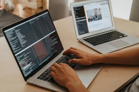Mains d'une personne tapant une consigne structurée sur le clavier d'un ordinateur portable posé sur un bureau.