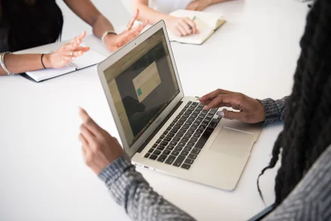 Une professionnelle assise devant son ordinateur de bureau fait un geste de refus poli de la main.