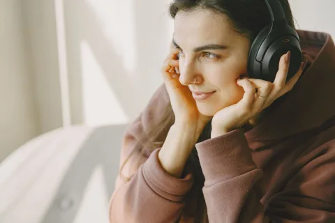 Une personne attentive ajuste les paramètres audio sur son smartphone en portant un casque de qualité.