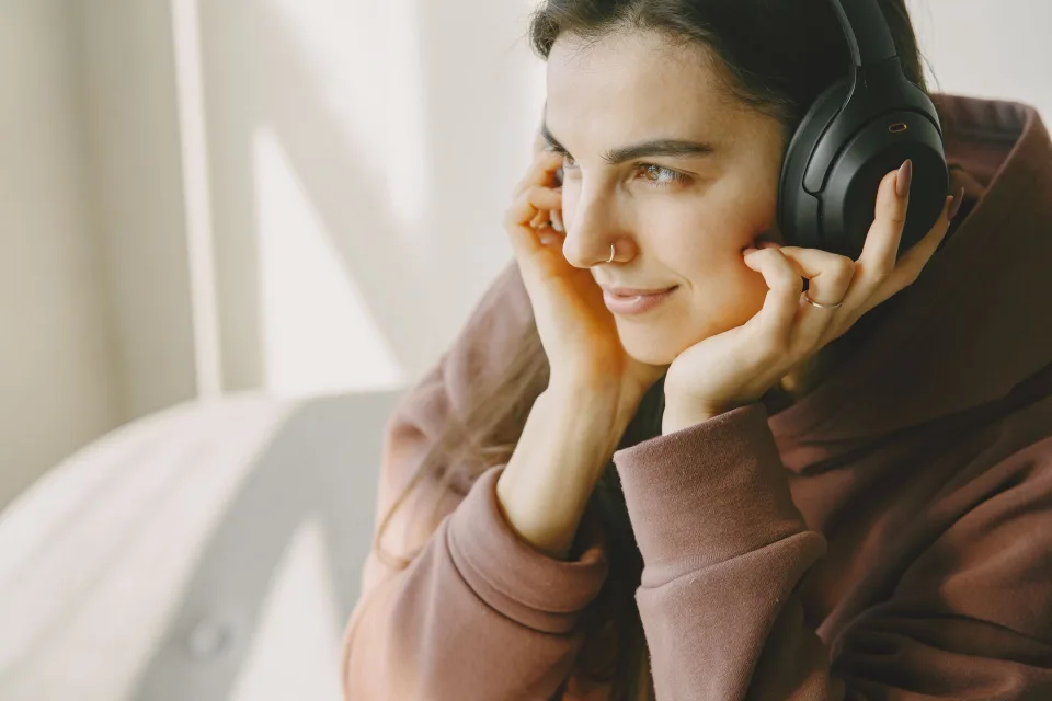 Une personne attentive ajuste les paramètres audio sur son smartphone en portant un casque de qualité.