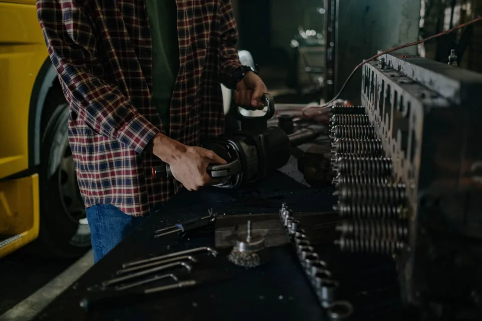 Un technicien spécialisé inspecte les modules d'une batterie de traction automobile ouverte sur une table d'atelier sécurisée.