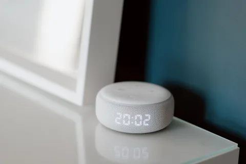 Un réveil connecté affichant une lumière douce orangée sur une table de chevet moderne.