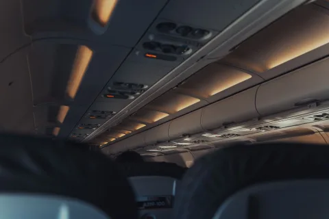 Un sac à dos souple de voyage glissé sous le siège passager d'un avion.