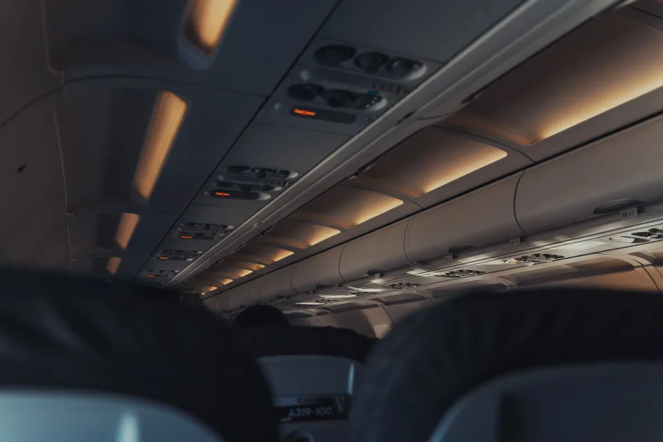Un sac à dos souple de voyage glissé sous le siège passager d'un avion.