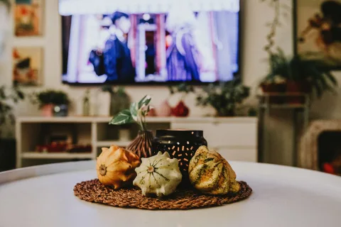 Un salon chaleureux décoré avec des coussins brun tabac et des accessoires d'automne posés sur une table en bois.