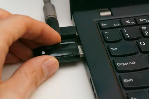 Une main insérant une clé de sécurité USB dans un ordinateur portable pour valider une connexion.