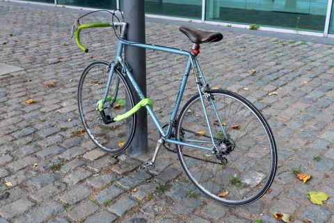 Un vélo électrique solidement attaché à un arceau métallique dans une rue avec un antivol en U.