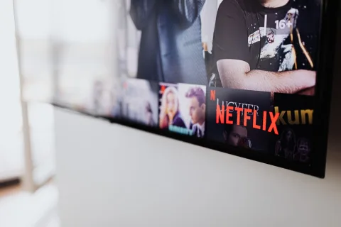 Un salon chaleureux dans la pénombre avec un écran de télévision allumé montrant un paysage de série télévisée.