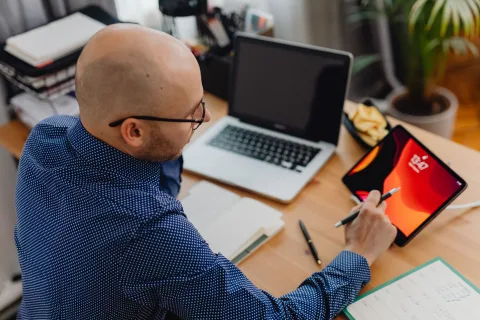 Un employé de bureau devant son ordinateur affichant un emploi du temps saturé de blocs de réunions.