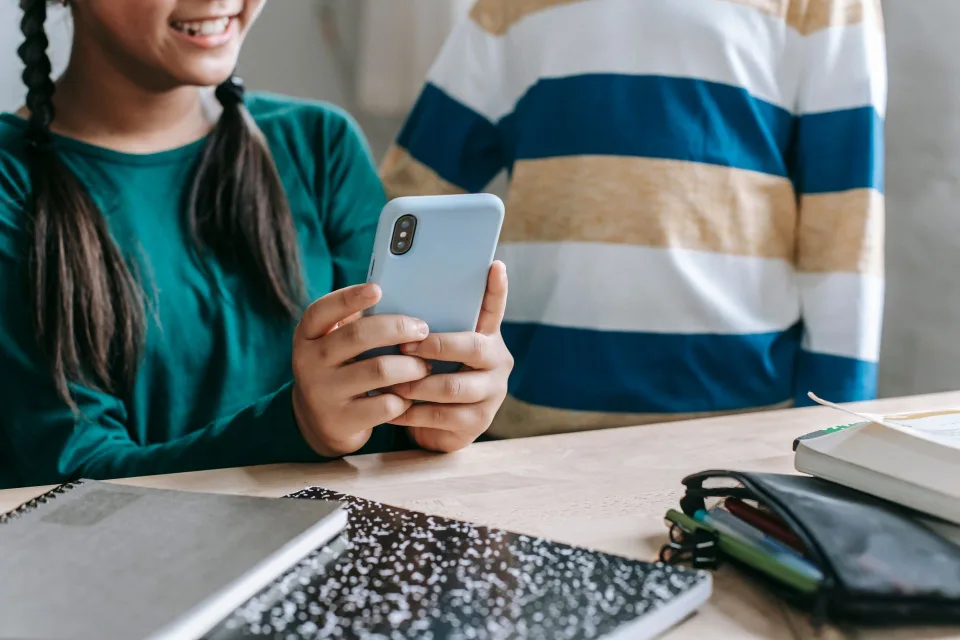 Un smartphone affichant un calendrier numérique à côté d'un ordinateur portable ouvert sur une interface scolaire.