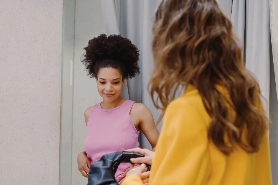 Une femme souriante assemble des vêtements d'automne devant son armoire ouverte.