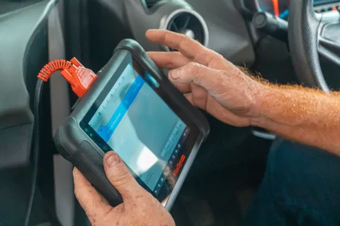 Un mécanicien branche un équipement de diagnostic électronique sur le port OBD d'un véhicule électrique d'occasion pour vérifier l'état de santé de la batterie.