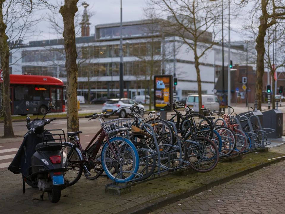 Un vélo de ville moderne doté d'une courroie de transmission en carbone noire garé contre un mur en briques.