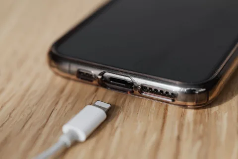 Un ancien smartphone relié à un casque audio de studio posé sur une table en bois rustique
