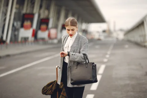Une voyageuse assise dans un aéroport moderne consulte un plan de la ville sur son téléphone portable à côté de ses bagages.