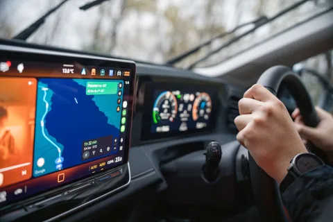 Écran tactile de voiture affichant l'interface Android Auto avec une carte de navigation et des icônes d'applications.