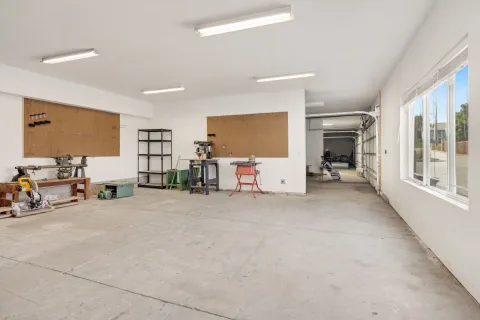 Des outils de bricolage bien rangés sur des étagères en bois dans un garage propre.