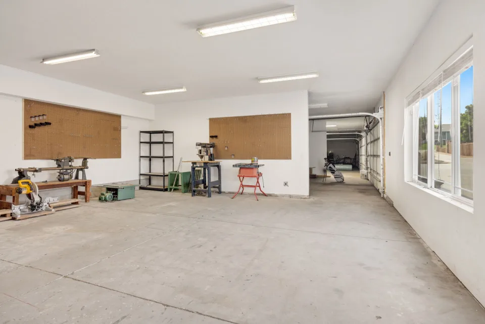 Des outils de bricolage bien rangés sur des étagères en bois dans un garage propre.