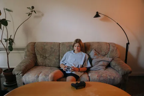 Un jeune garçon concentré qui joue à la console dans un salon lumineux