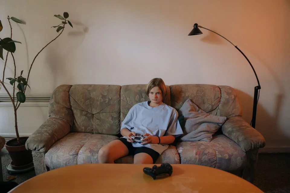 Un jeune garçon concentré qui joue à la console dans un salon lumineux