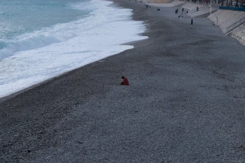 Une plage de galets déserte à Nice sous un soleil d'hiver avec une mer calme.