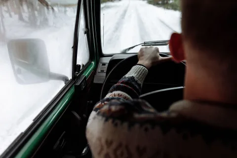 Une personne pulvérise un liquide dégivrant sur le pare-brise gelé d'une voiture le matin.