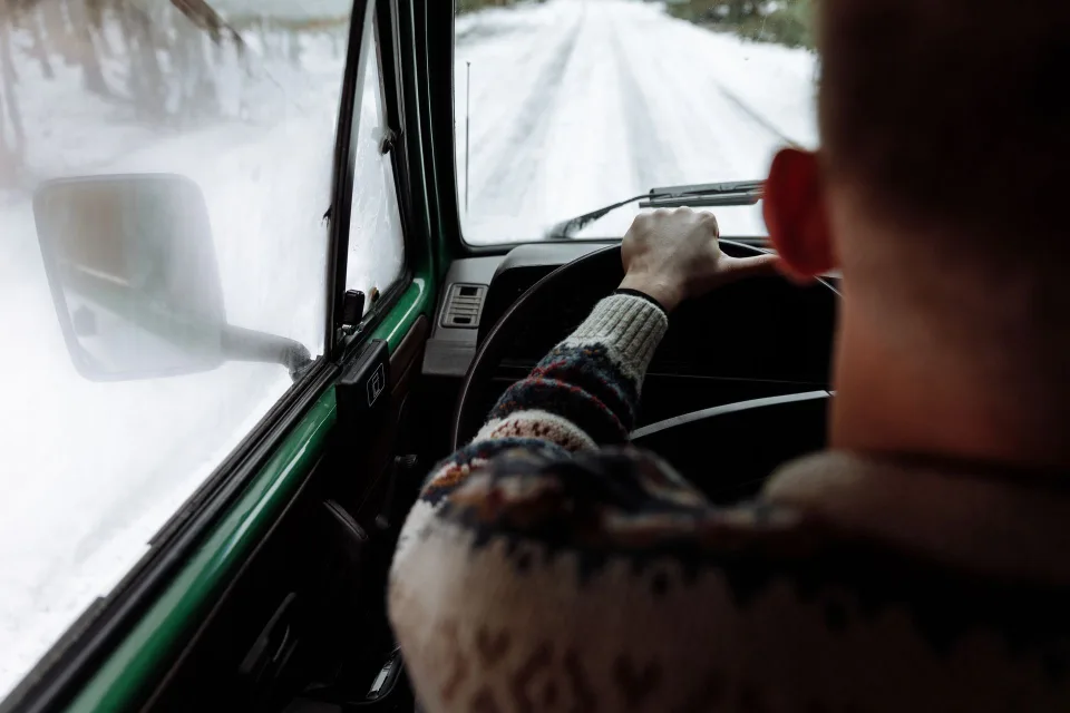 Une personne pulvérise un liquide dégivrant sur le pare-brise gelé d'une voiture le matin.