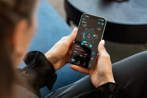 Un smartphone affichant une application de contrôle domotique posé à côté d'une box internet dans un salon.
