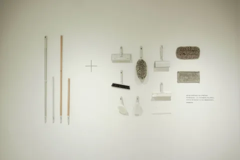 Une personne utilise un goupillon flexible pour dépoussiérer l'intérieur d'un radiateur blanc.
