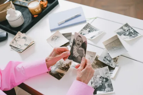 Une personne utilise son smartphone pour numériser une vieille photographie en noir et blanc posée sur une table en bois.