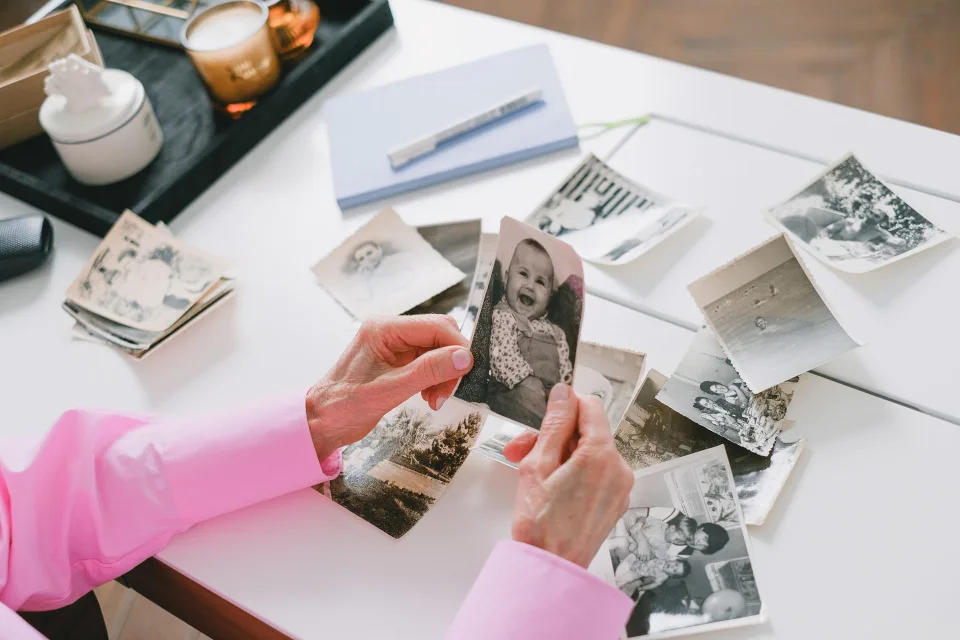 Une personne utilise son smartphone pour numériser une vieille photographie en noir et blanc posée sur une table en bois.