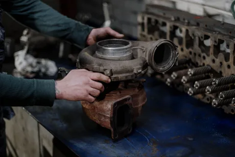 Un mécanicien examine une pièce de carrosserie d'occasion dans un garage professionnel.