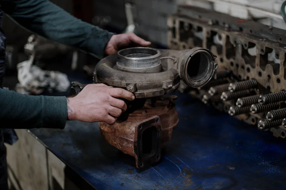 Un mécanicien examine une pièce de carrosserie d'occasion dans un garage professionnel.