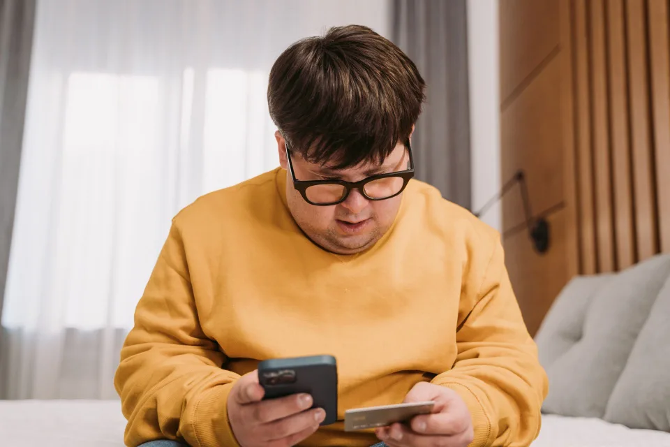Une personne surprise en consultant ses comptes bancaires sur son smartphone.