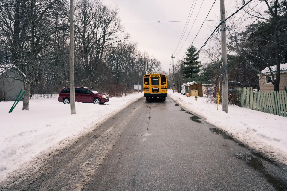 Un autocar scolaire circulant sur une route de campagne française sous un ciel clair.