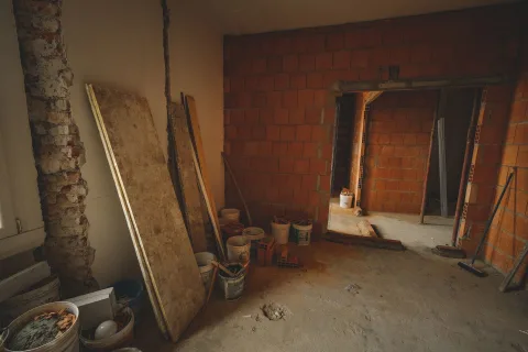 Un ouvrier mesure la hauteur d'un mur en briques séparant deux jardins.